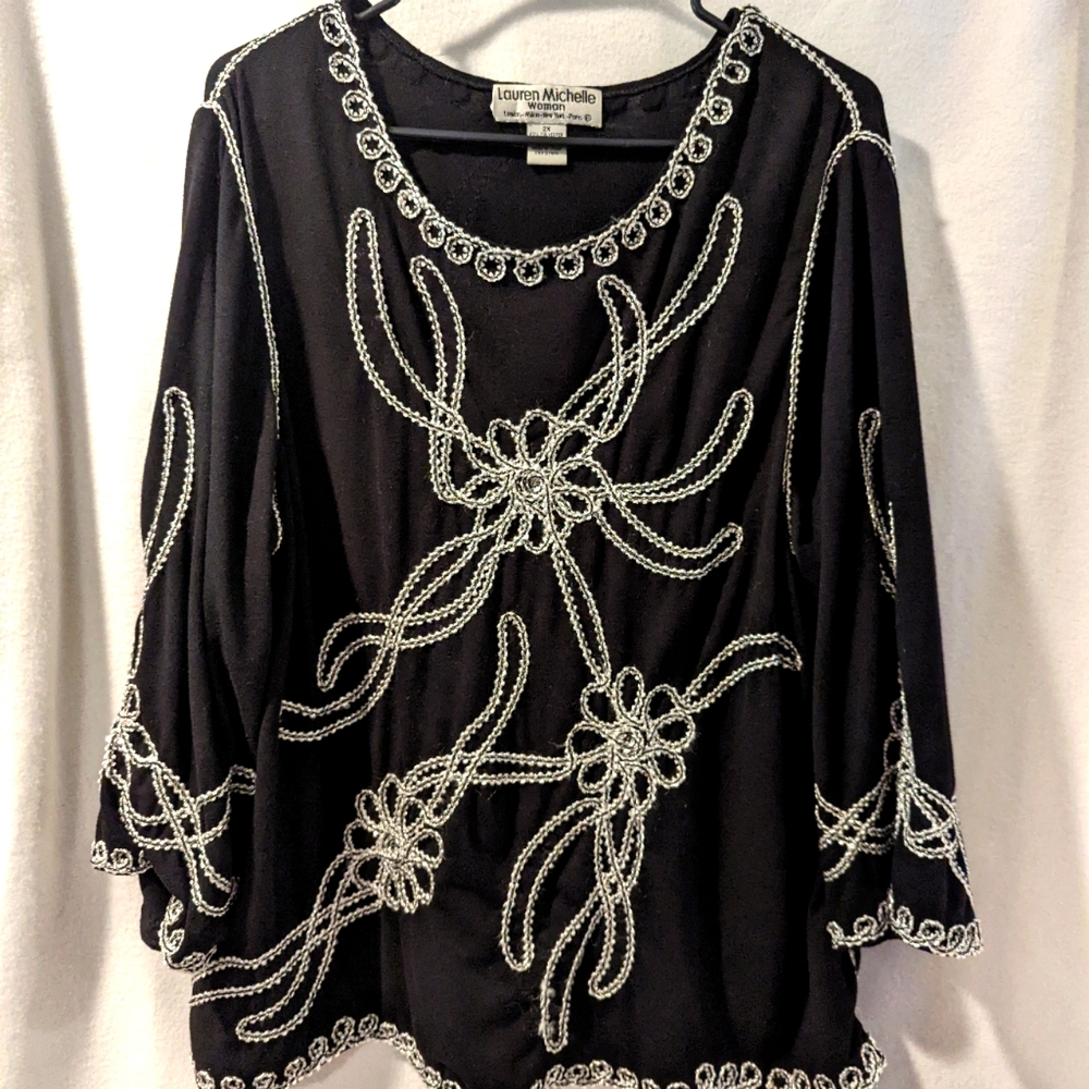 Lauren Michelle Woman black top with white and silver applique.